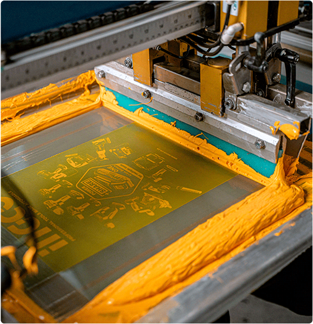 Close-up of screen printing process applying yellow ink to fabric showcasing Barron’s custom branding and apparel decoration services